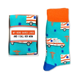 May include: A gift box containing a pair of blue socks with a pattern of white ambulances and red medical symbols. The box has a white label with the text "My hero saves lives and I call her mom."