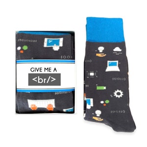 May include: A pair of black socks with a blue cuff. The socks feature a pattern of computer-related icons, including a laptop, a cloud, a lightbulb, and a keyboard. The socks are packaged in a white box with the text "GIVE ME A <br/>" printed on the front.