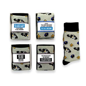 Puede incluir: Cinco calcetines grises con dise&ntilde;os de coches de polic&iacute;a y insignias. Cuatro pares est&aacute;n en cajas con etiquetas como "Sus luces parpadean" y "&iexcl;Totalmente incre&iacute;ble!"