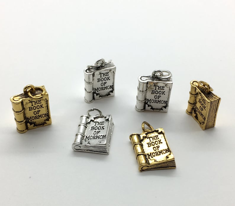 May include: Five silver and gold charms shaped like closed books with the words "The Book of Mormon" inscribed on them.