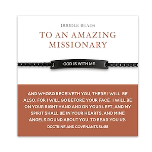 May include: Black bracelet with a rectangular plate that reads "GOD IS WITH ME." The card reads "TO AN AMAZING MISSIONARY" and includes a religious quote. The brand name "DOODLE BEADS" is at the top.