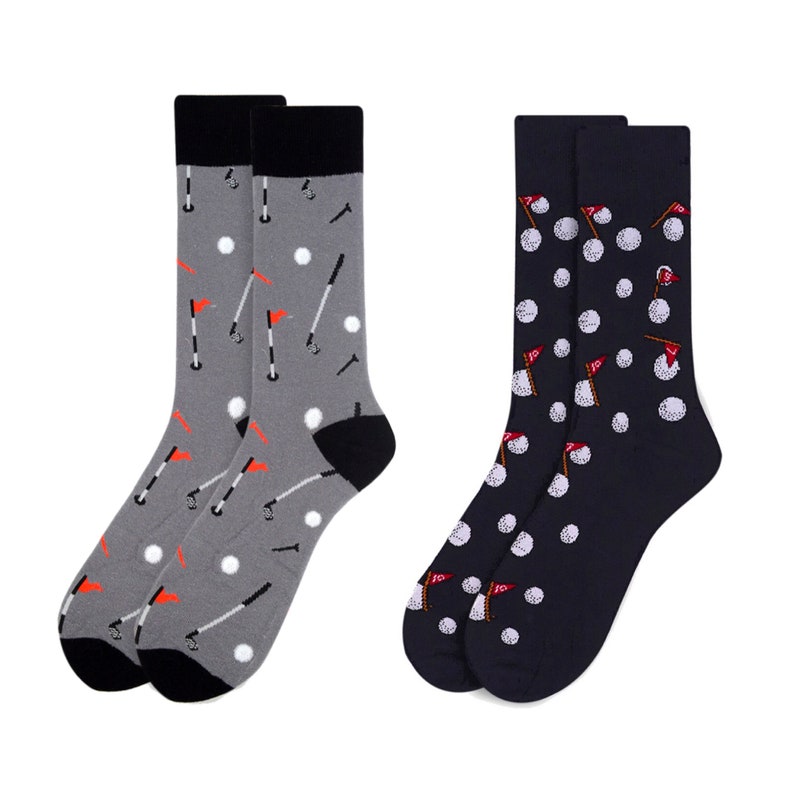 May include: Two pairs of socks with a golf theme. One pair is gray with white golf balls, red flags, and golf clubs. The other pair is navy blue with white golf balls and red flags.
