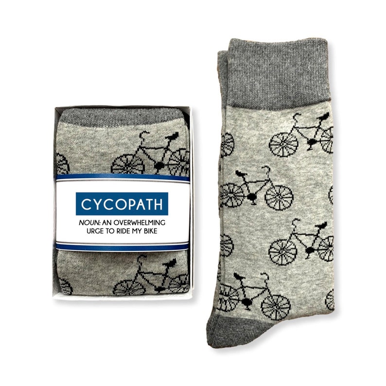 May include: A pair of gray socks with a black bicycle pattern. The socks come in a box with the text "CYCOPATH NOUN: AN OVERWHELMING URGE TO RIDE MY BIKE".