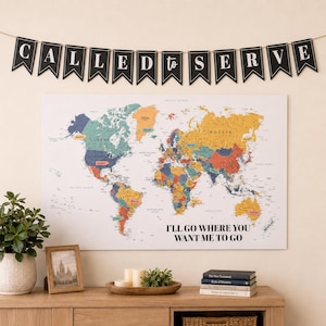May include: A wall-mounted world map poster featuring colorful continents and the text I'LL GO WHERE YOU WANT ME TO GO, displayed below a black pennant banner with white letters spelling CALLED TO SERVE, hanging on a light-colored wall.