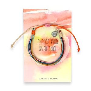 May include: A colorful friendship bracelet with a silver charm that says "Choose Kind Over Cool". The bracelet is on a card with a watercolor background and the words "Doodle Beads" at the bottom.