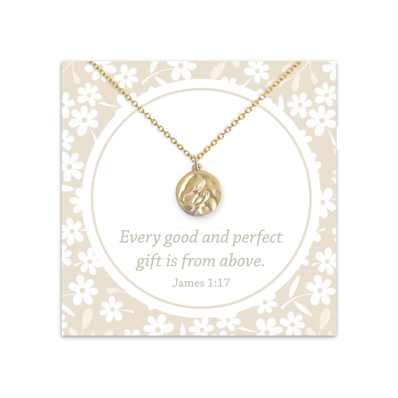 May include: Gold necklace with a round pendant featuring a textured image of two hands clasped together. The card reads "Every good and perfect gift is from above. James 1:17".