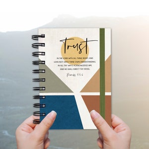 May include: A spiral bound journal with a geometric design in shades of brown, blue, and green. The cover features the word "Trust" in black lettering and a Bible verse from Proverbs 3:5-6.