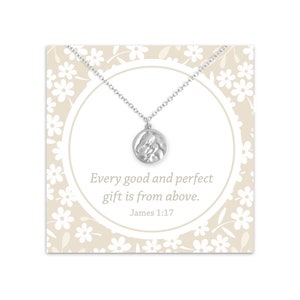 May include: Silver necklace with a round pendant featuring a textured image of two hands clasped together. The pendant is on a card with a white floral pattern and the text "Every good and perfect gift is from above. James 1:17"