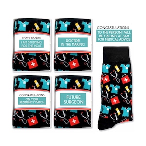 May include: Four black and white gift boxes with colorful socks inside. Each box has a different message on the front. The socks have a pattern of medical symbols, including a stethoscope, a first aid kit, and a doctor's coat. The message on the boxes are: "I have no life I am studying for the MCAT", "Doctor in the making", "Congratulations on your residency match", and "Future Surgeon".
