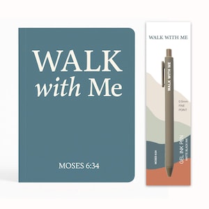 May include: A teal-colored journal and a pen are displayed against a white background. The journal cover reads "WALK with Me" with "MOSES 6:34" below. The pen is matte black and comes with a matching bookmark that reads "WALK WITH ME".