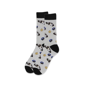 Puede incluir: Un par de calcetines grises con talones y dedos negros. Los calcetines presentan un estampado de coches de polic&iacute;a, insignias y sombreros en azul, amarillo y blanco. La parte superior de los calcetines es negra.