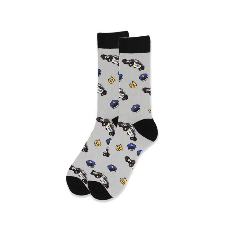 Puede incluir: Un par de calcetines grises con talones y dedos negros. Los calcetines presentan un estampado de coches de polic&iacute;a, insignias y sombreros en azul, amarillo y blanco. La parte superior de los calcetines es negra.