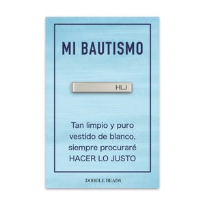Könnte beinhalten: Eine hellblaue Karte mit dem Text "MI BAUTISMO" und einem silbernen Balken mit der Gravur "HLJ". Die Karte enthält auch spanischen Text und den Markennamen "DOODLE BEADS".