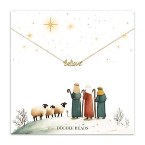 May include: A gold-colored necklace with the word "believe" in cursive script. The necklace is displayed on a card with an illustration of three shepherds, sheep, and a star. The text "DOODLE BEADS" is at the bottom of the card.