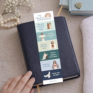 May include: A navy blue leather-bound book with a bookmark featuring the text "My Baptismal Covenants" and illustrations. The bookmark includes the text "Take upon yourself the name of Christ," "Always Remember Him," "Keep His Commandments," "We are forgiven, if we repent," "Serve Him to the end," and "Always have His Spirit."