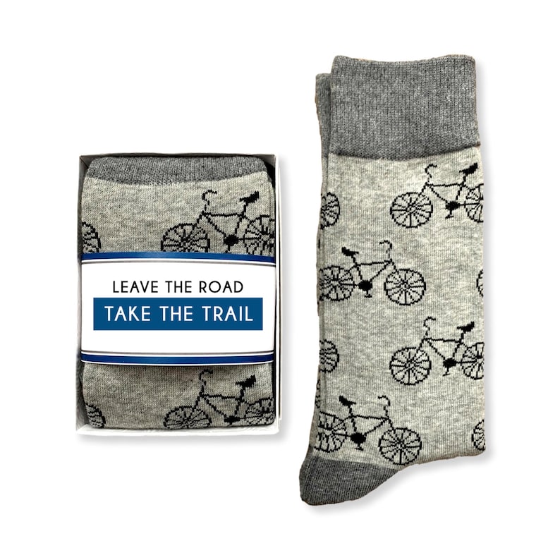 May include: A pair of gray socks with a black bicycle pattern. The socks come in a white box with the text "Leave the road, take the trail".
