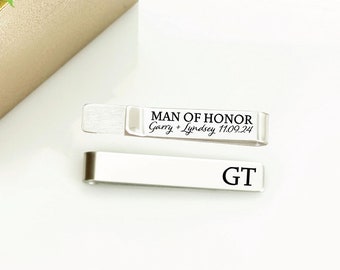 May include: Silver tie clip with the text "MAN OF HONOR Gary + Lindsey 11.09.24" and the initials "GT" engraved on the front.