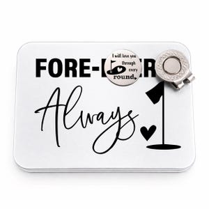 May include: A white golf ball marker tin with the words "FOREVER Always" in black. A golf ball marker with a flag and heart design is attached, along with a silver-colored golf ball marker clip.