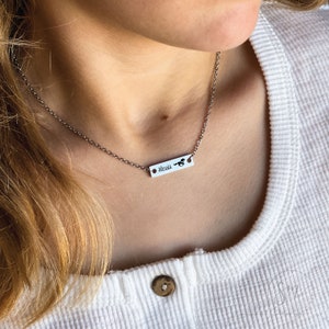 K&ouml;nnte beinhalten: Eine silberne Kettenkette mit einem kleinen silbernen Bar-Anh&auml;nger, auf dem "Alessia" steht, und einem kleinen Pferde-Anh&auml;nger auf der rechten Seite der Bar.