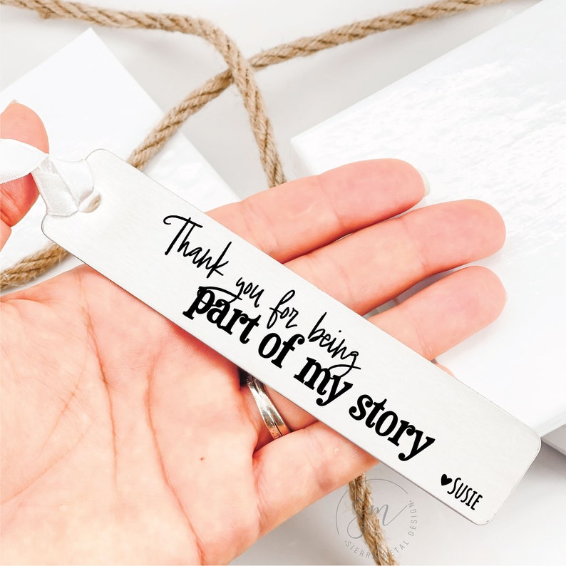 May include: Silver bookmark with the text "Thank you for being part of my story" and a heart with the name "Susie" below it.