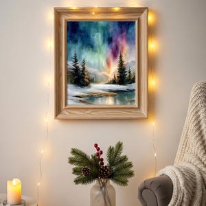 Puede incluir: Una pintura en acuarela enmarcada representa un paisaje invernal con una colorida aurora boreal. El marco de madera rodea la obra de arte, que presenta &aacute;rboles de hoja perenne, un suelo nevado y una masa de agua reflectante. La escena est&aacute; iluminada por luces de cadena.