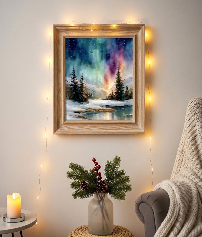 Puede incluir: Una pintura en acuarela enmarcada representa un paisaje invernal con una colorida aurora boreal. El marco de madera rodea la obra de arte, que presenta &aacute;rboles de hoja perenne, un suelo nevado y una masa de agua reflectante. La escena est&aacute; iluminada por luces de cadena.