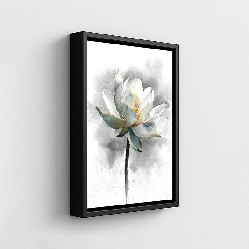 May include: A framed watercolor painting of a white lotus flower with a yellow center and green-tinged petals. The flower is set against a soft, gray and white background. The black frame adds a modern touch to the floral artwork.