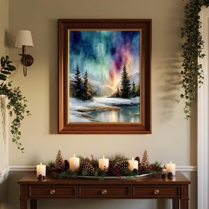 Puede incluir: Una pintura de paisaje enmarcada representa una escena invernal con una colorida aurora boreal. La obra de arte est&aacute; en un marco de madera oscura y cuelga sobre una consola de madera. La mesa est&aacute; decorada con velas, pi&ntilde;as y vegetaci&oacute;n.