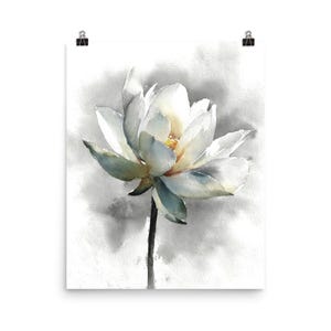 May include: Watercolor print of a white lotus flower with a yellow center and subtle blue-green accents on the petals. The flower is set against a soft, gray watercolor background, creating a serene and elegant aesthetic.