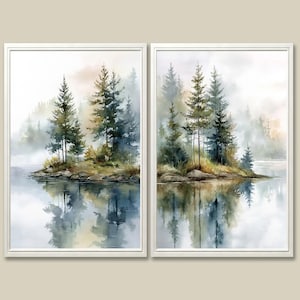 May include: Two framed watercolor paintings depict a serene landscape. Each features a small island with evergreen trees reflected in the calm water. The artwork evokes a misty, natural scene with soft colors and a tranquil atmosphere.