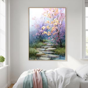 May include: Watercolor painting of a serene garden path. The artwork features a stone pathway leading through a lush landscape with blooming trees in shades of pink and yellow. The painting is framed in a light wood.