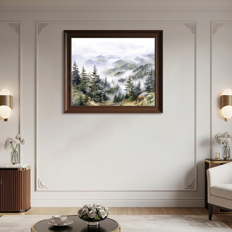 May include: A framed watercolor painting of a misty mountain landscape. The artwork depicts evergreen trees and rolling hills shrouded in fog. The frame is a dark brown color, and the painting is displayed on a white wall.