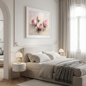 May include: A framed artwork featuring a soft, impressionistic painting of pink roses. The painting hangs above a bed with white bedding and a gray throw blanket. Two bedside tables with lamps flank the bed, creating a serene bedroom scene.