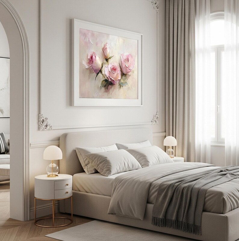 May include: A framed artwork featuring a soft, impressionistic painting of pink roses. The painting hangs above a bed with white bedding and a gray throw blanket. Two bedside tables with lamps flank the bed, creating a serene bedroom scene.