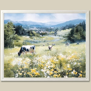 May include: A framed watercolor painting of a pastoral scene. Cows graze in a field of wildflowers, with a backdrop of rolling hills and a distant village. The artwork features a palette of greens, blues, and yellows.