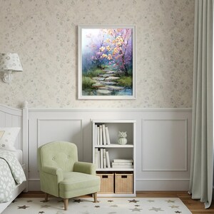 May include: A framed watercolor painting depicts a serene path through a flowering garden. The artwork features a stone pathway leading to a stream, with trees in bloom. The painting is displayed above a white bookshelf and a green armchair.