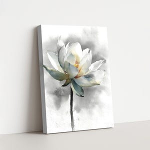 May include: A canvas print featuring a watercolor painting of a white lotus flower. The flower has delicate petals with hints of blue and yellow, set against a soft gray and white background. The stem is a dark gray.
