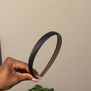 May include: A black satin headband. The headband is thin and has a simple design.