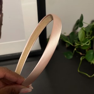 May include: A light pink satin headband. The headband is thin and flexible.