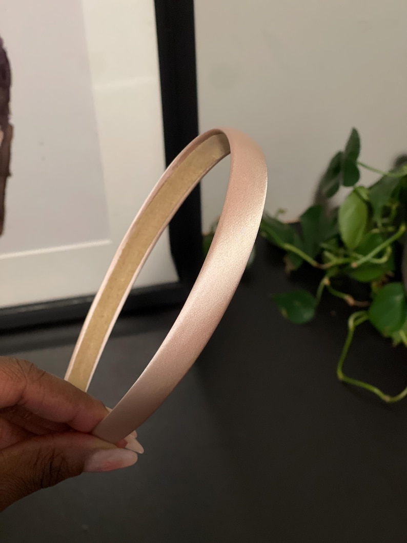 May include: A light pink satin headband. The headband is thin and flexible.