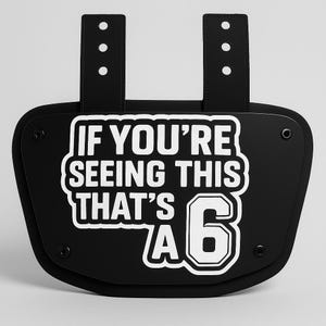 May include: Black football shoulder pad with white text that reads "If you're seeing this that's a 6".