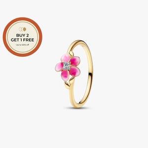 Könnte beinhalten: Ein goldfarbener Ring mit einer fünfblättrigen Blume mit rosa Emaille-Verlauf und einem quadratischen, klaren Stein in der Mitte. Ein kreisförmiges Abzeichen in der oberen linken Ecke zeigt den Text BUY 2 GET 1 FREE Up to 50% off.