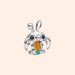 May include: A silver-colored charm depicting a cartoon rabbit holding a carrot. The rabbit has large eyes and long ears. The carrot is orange, and the charm has a green accent.