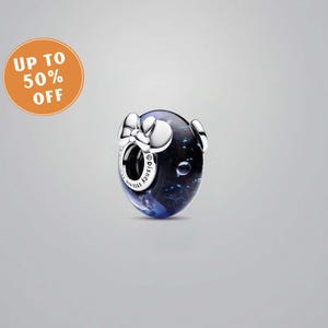 Pode incluir: Um berloque com um design azul escuro e preto, apresentando um la&ccedil;o prateado e dois pequenos c&iacute;rculos prateados. O berloque tem a palavra "Disney" e "S925 ALE" gravadas. Um c&iacute;rculo laranja com o texto "UP TO 50% OFF" est&aacute; no canto superior esquerdo.