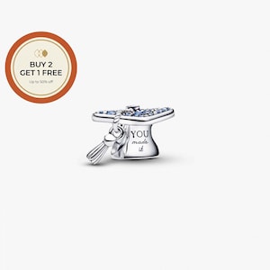 May include: A silver graduation cap charm with blue accents and a dangling tassel. The charm has the words "YOU made it" engraved on the side. A round orange and white graphic with text is in the upper left corner.