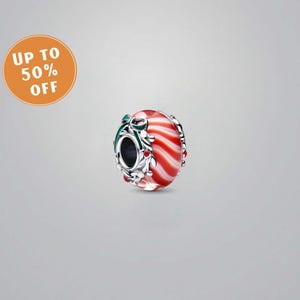 May include: A red and white striped glass bead with silver detailing. The bead features a green bow and a wreath design. An orange circle in the upper left corner displays the text "UP TO 50% OFF".