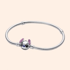 Puede incluir: Una pulsera plateada con un charm del personaje Stitch de la pel&iacute;cula Lilo & Stitch. El charm muestra la cara de Stitch, con orejas rosas y detalles azules. La pulsera tiene un dise&ntilde;o de cadena de serpiente. Mide unos 18 cm.