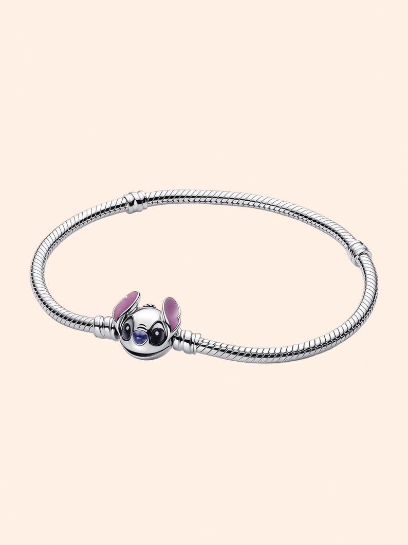 Puede incluir: Una pulsera plateada con un charm del personaje Stitch de la pel&iacute;cula Lilo & Stitch. El charm muestra la cara de Stitch, con orejas rosas y detalles azules. La pulsera tiene un dise&ntilde;o de cadena de serpiente. Mide unos 18 cm.