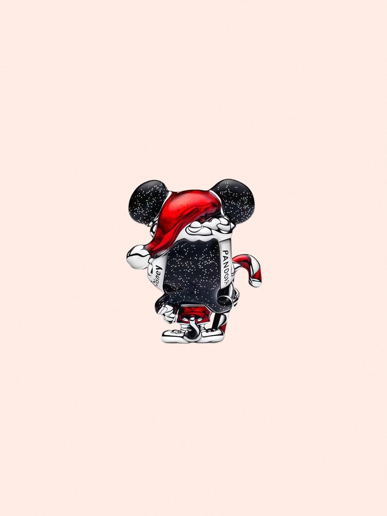 Peut inclure: Un charm en argent repr&eacute;sentant Mickey Mouse avec un bonnet de P&egrave;re No&euml;l rouge, tenant un parchemin. Le charm a des oreilles noires avec des mouchetures blanches et des d&eacute;tails rouges et blancs. Le parchemin porte les mots "Pandora" et "Disney".