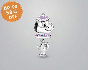 May include: A silver charm with a teapot design, featuring a purple lid and accents. The charm has a smiling face and a small teacup hanging below. Likely a pendant or bead for a bracelet.